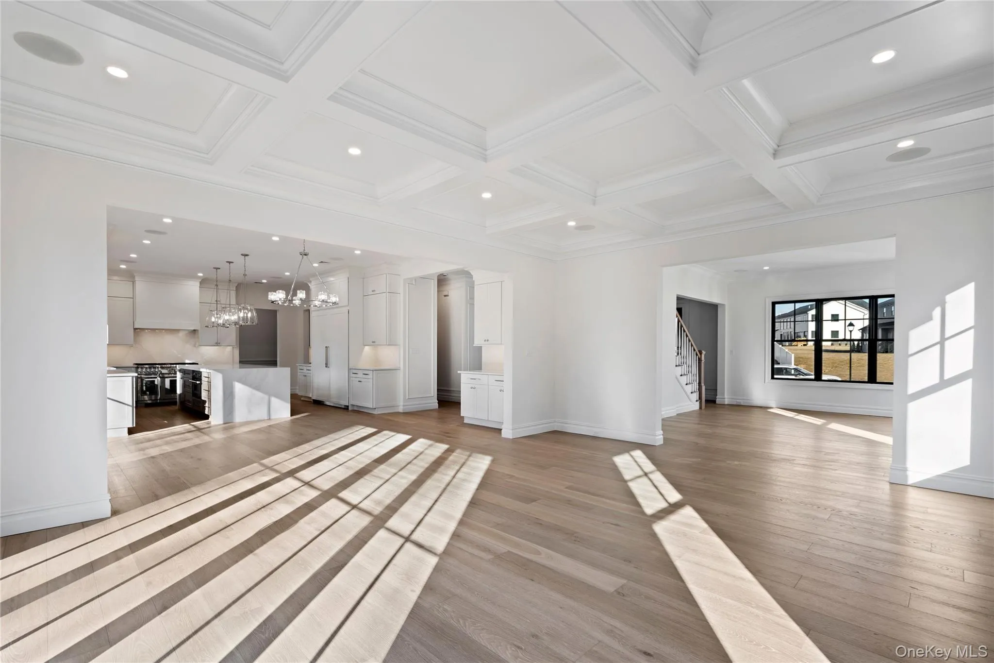 Unfurnished living room with recessed lighting, coffered ceiling, a chandelier, light wood finished floors, and beamed ceiling Unfurnished living room with recessed lighting, coffered ceiling, a chandelier, light wood finished floors, and beamed ceiling