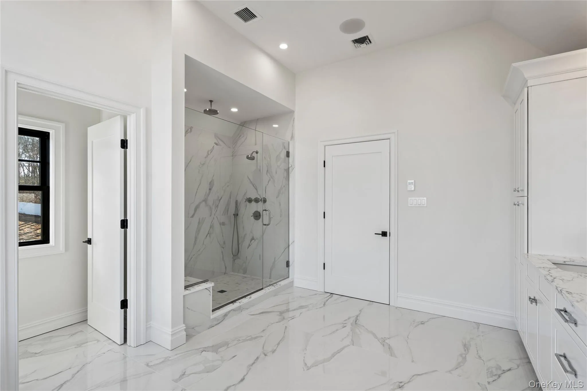 Bathroom with a marble finish shower, light marble finish flooring, vanity, and recessed lighting Bathroom with a marble finish shower, light marble finish flooring, vanity, and recessed lighting