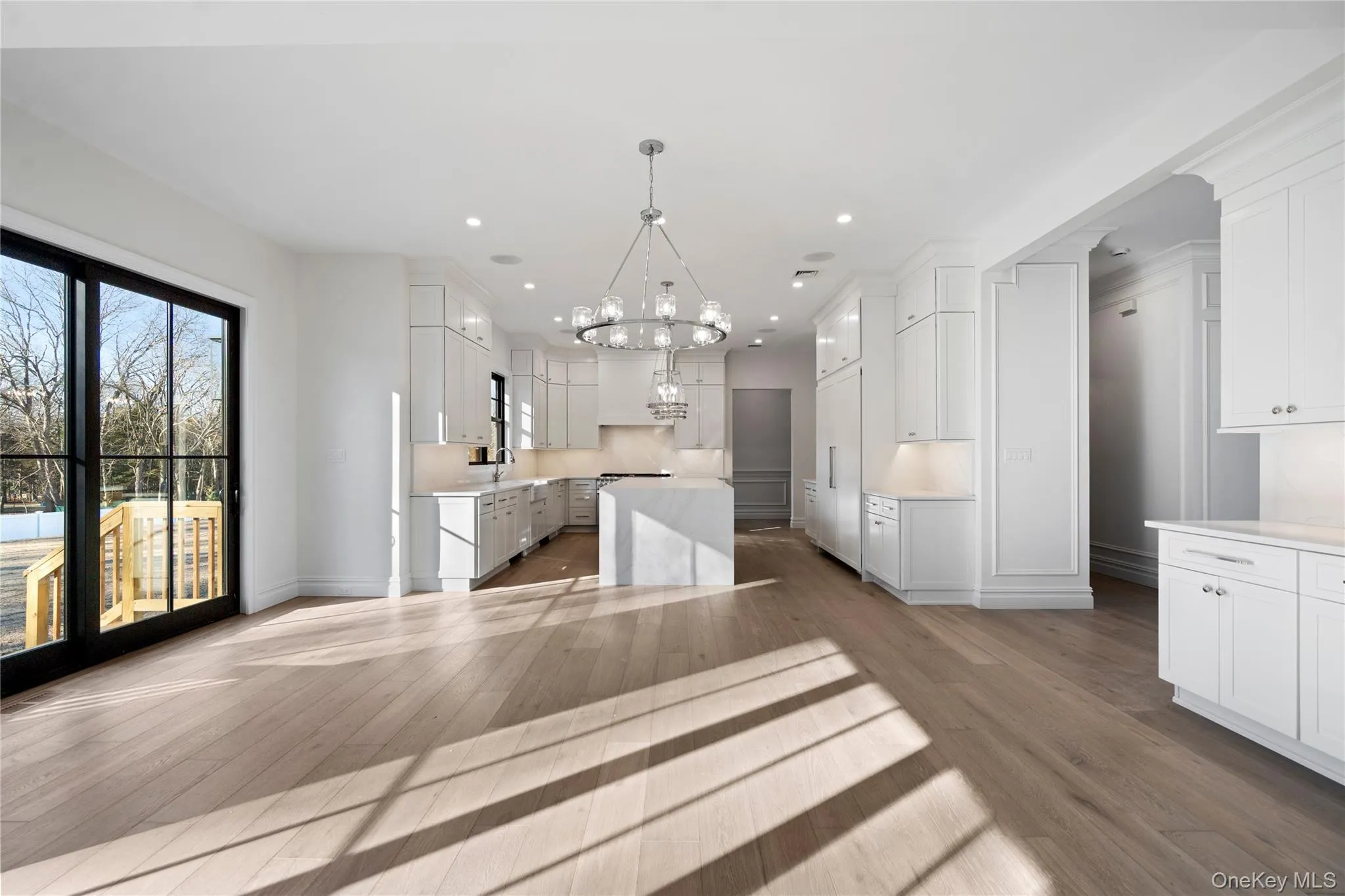 Kitchen with light stone countertops, white cabinets, pendant lighting, a chandelier, and a center island Kitchen with light stone countertops, white cabinets, pendant lighting, a chandelier, and a center island