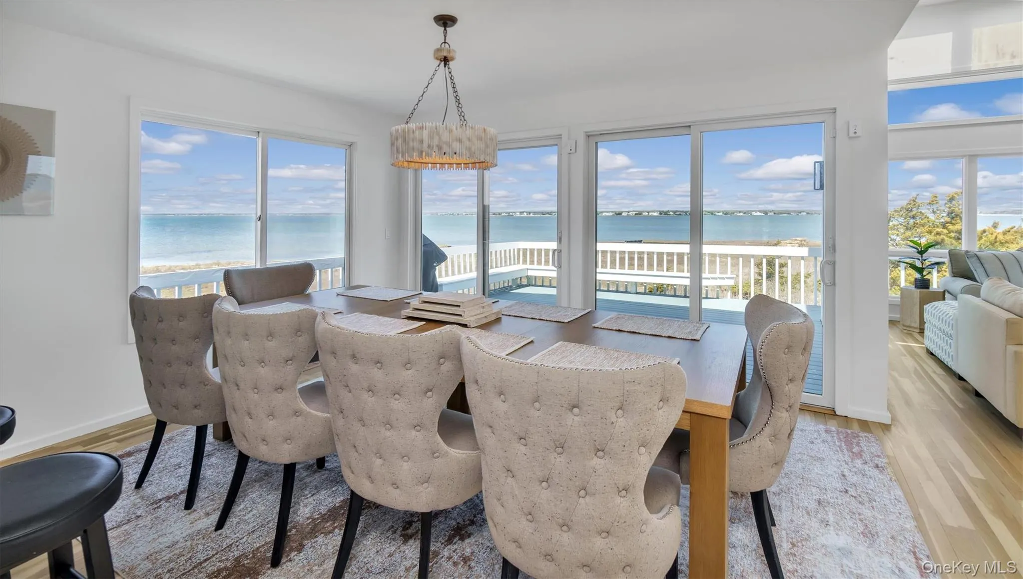 Dining space with baseboards, light wood-type flooring, an inviting chandelier, and a water view Dining space with baseboards, light wood-type flooring, an inviting chandelier, and a water view