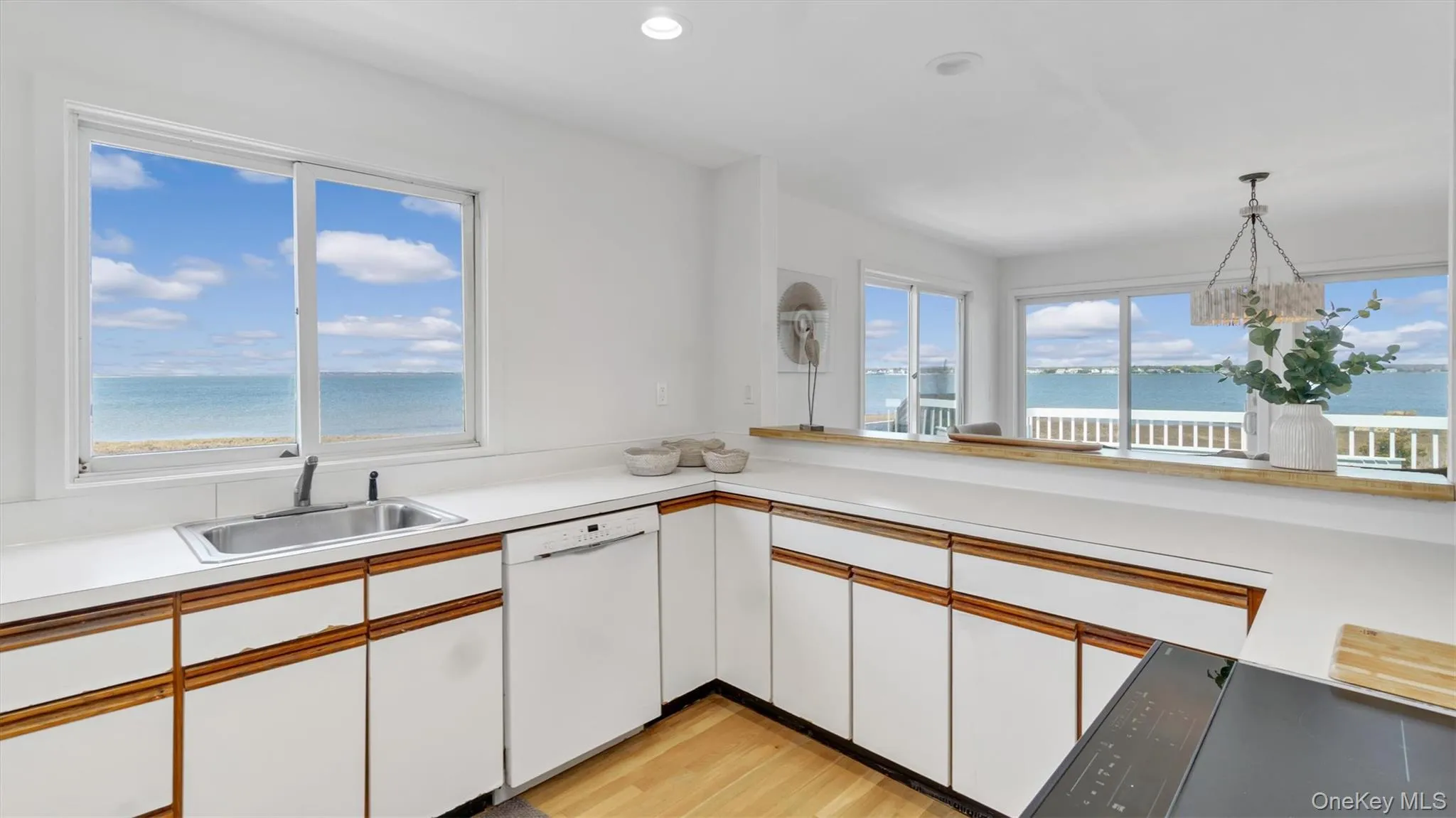 Kitchen featuring light countertops, dishwasher, light wood finished floors, a sink, and white cabinetry Kitchen featuring light countertops, dishwasher, light wood finished floors, a sink, and white cabinetry