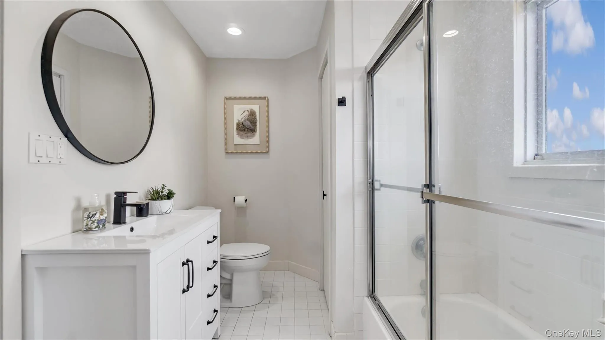 Shared Full bathroom featuring tile patterned floors, combined bath / shower with glass door, toilet, vanity, and baseboards Shared Full bathroom featuring tile patterned floors, combined bath / shower with glass door, toilet, vanity, and baseboards