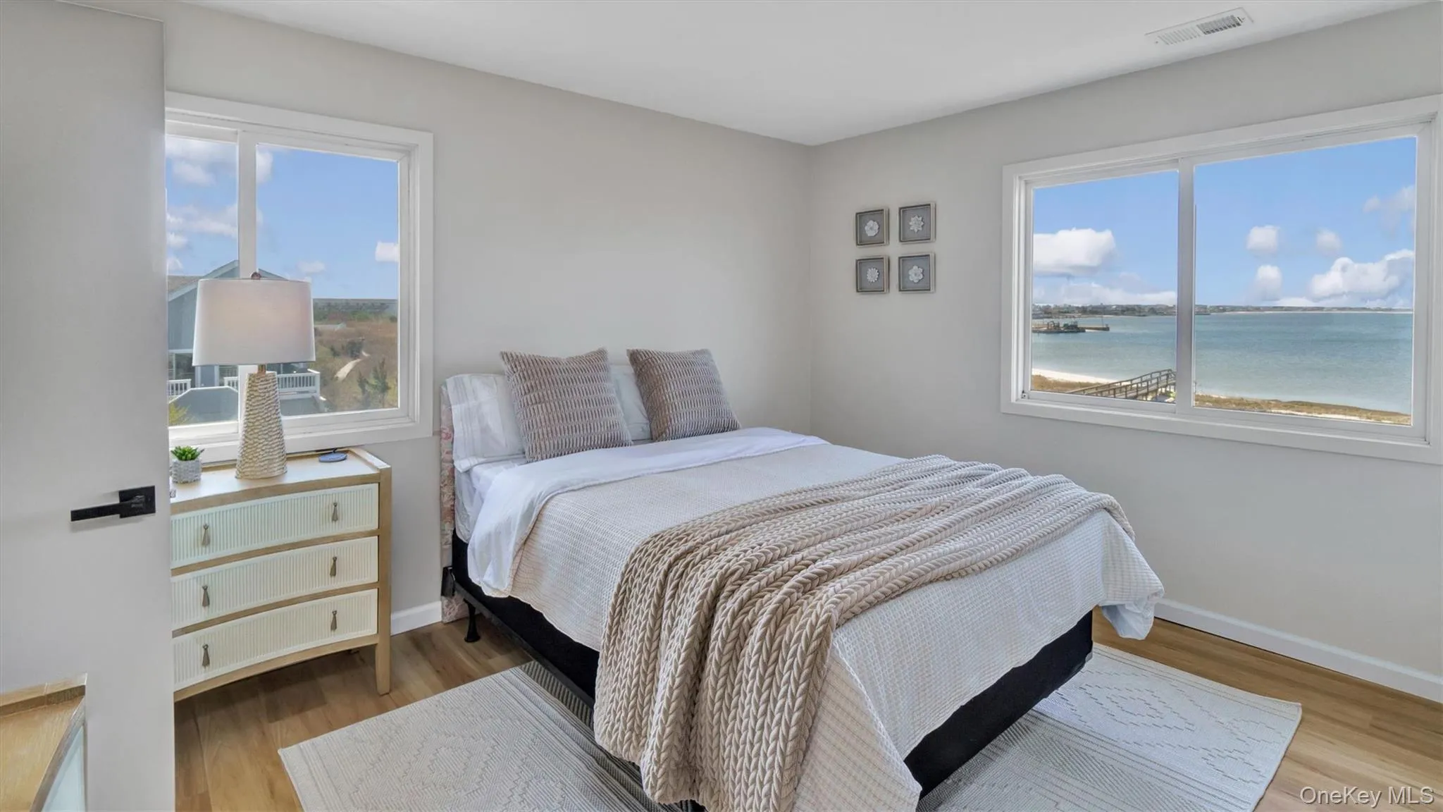 Bedroom with baseboards, visible vents, wood finished floors, and multiple windows Bedroom with baseboards, visible vents, wood finished floors, and multiple windows