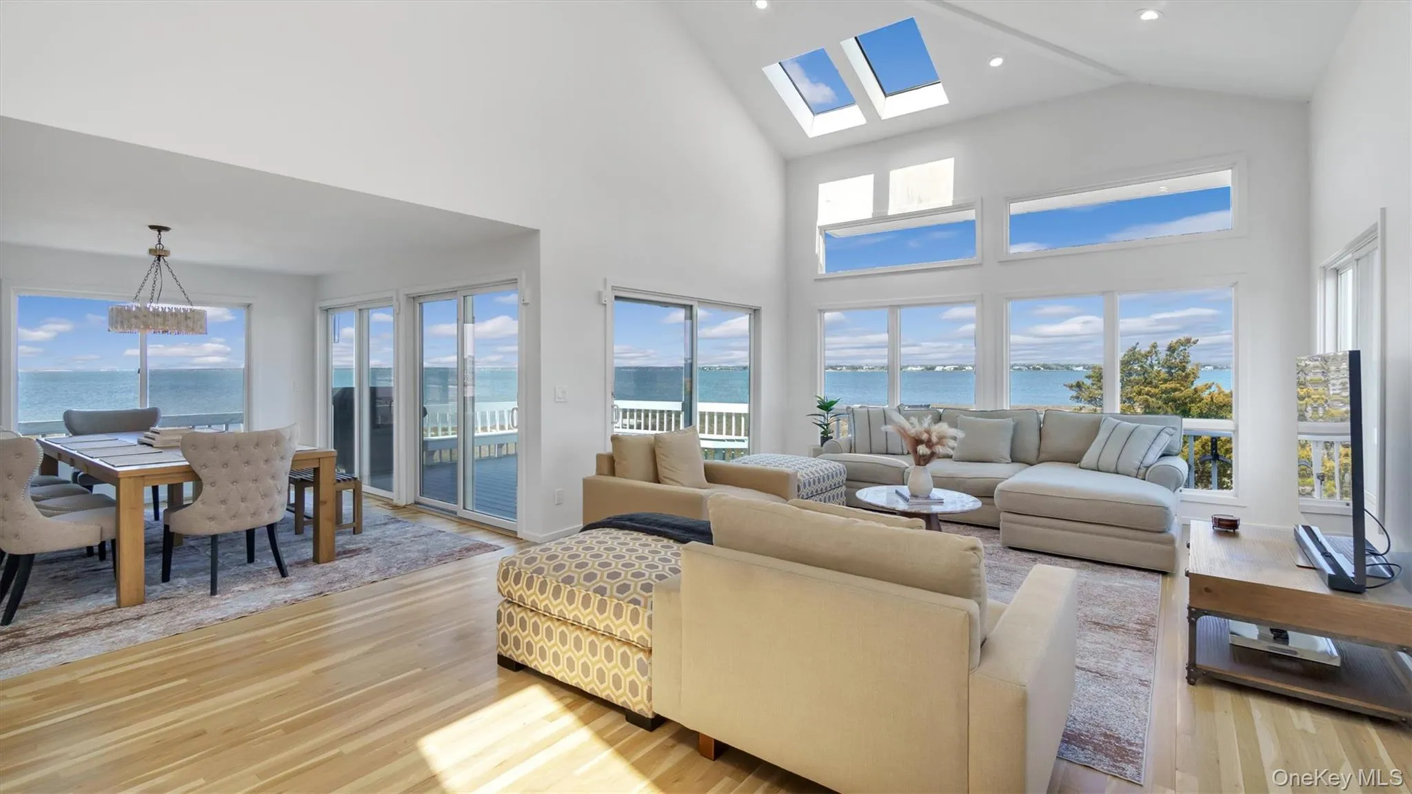 Living area with light wood-style flooring, a healthy amount of sunlight, and high vaulted ceiling Living area with light wood-style flooring, a healthy amount of sunlight, and high vaulted ceiling