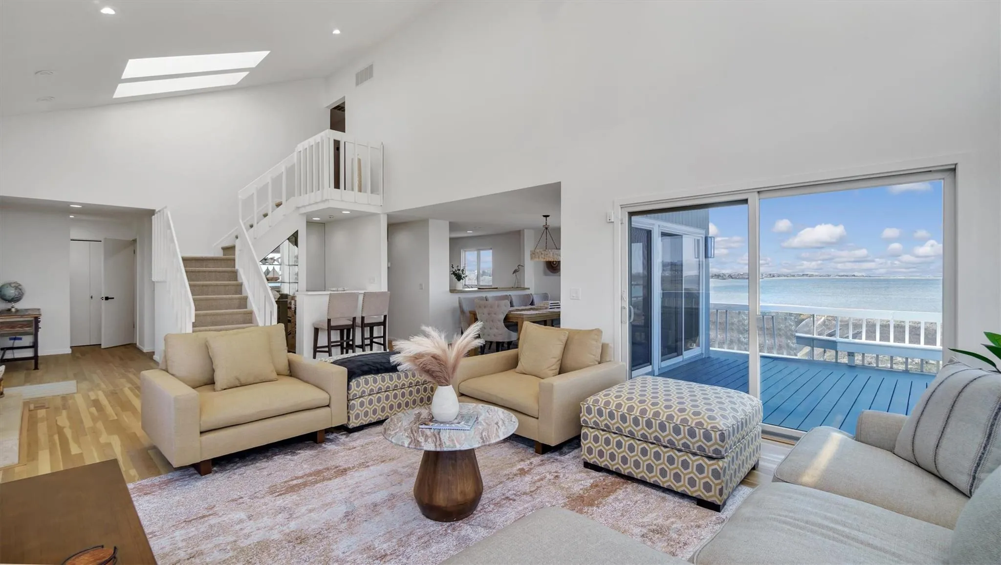 Living area featuring a wealth of natural light, high vaulted ceiling, a water view, and a skylight Living area featuring a wealth of natural light, high vaulted ceiling, a water view, and a skylight