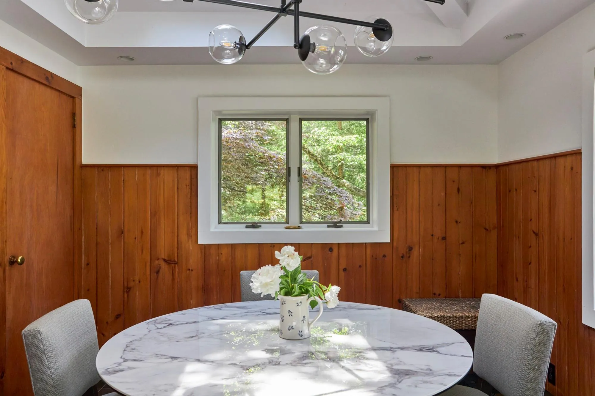 Dining area with wainscoting, wooden walls, and an inviting chandelier Dining area with wainscoting, wooden walls, and an inviting chandelier