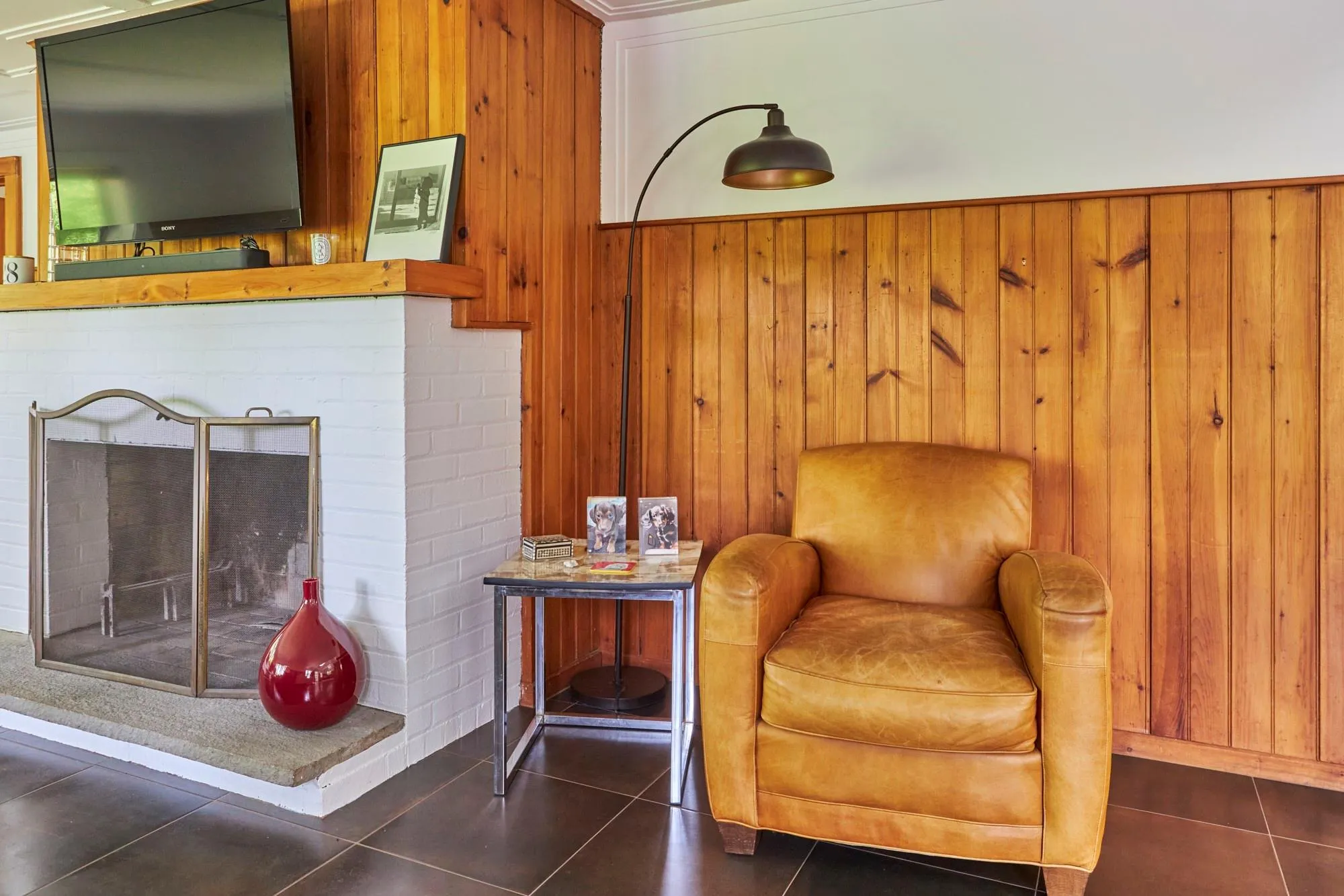 Living area with a fireplace, wooden walls, and dark tile patterned floors Living area with a fireplace, wooden walls, and dark tile patterned floors