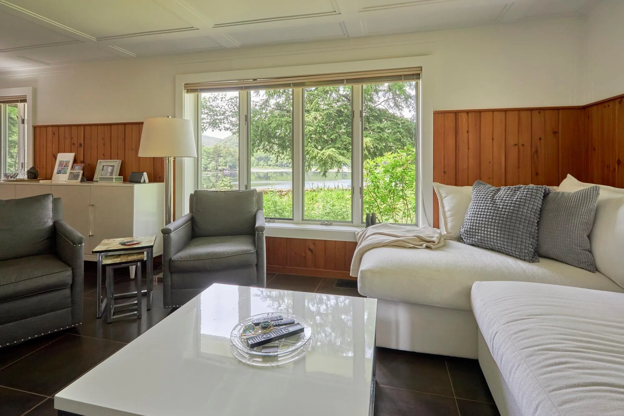 Living area featuring a wealth of natural light, wooden walls, and dark tile patterned flooring Living area featuring a wealth of natural light, wooden walls, and dark tile patterned flooring