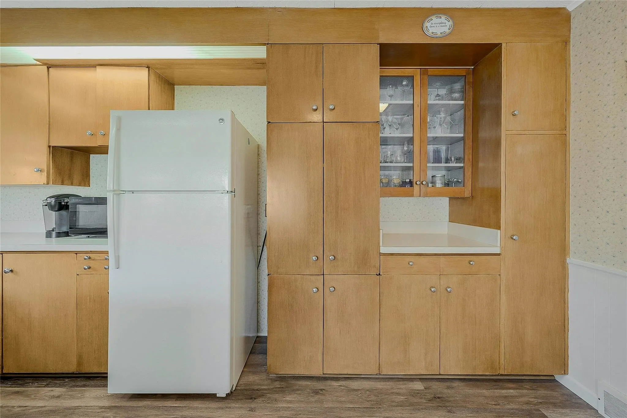Kitchen featuring a wainscoted wall, light countertops, wood finished floors, and freestanding refrigerator Kitchen featuring a wainscoted wall, light countertops, wood finished floors, and freestanding refrigerator