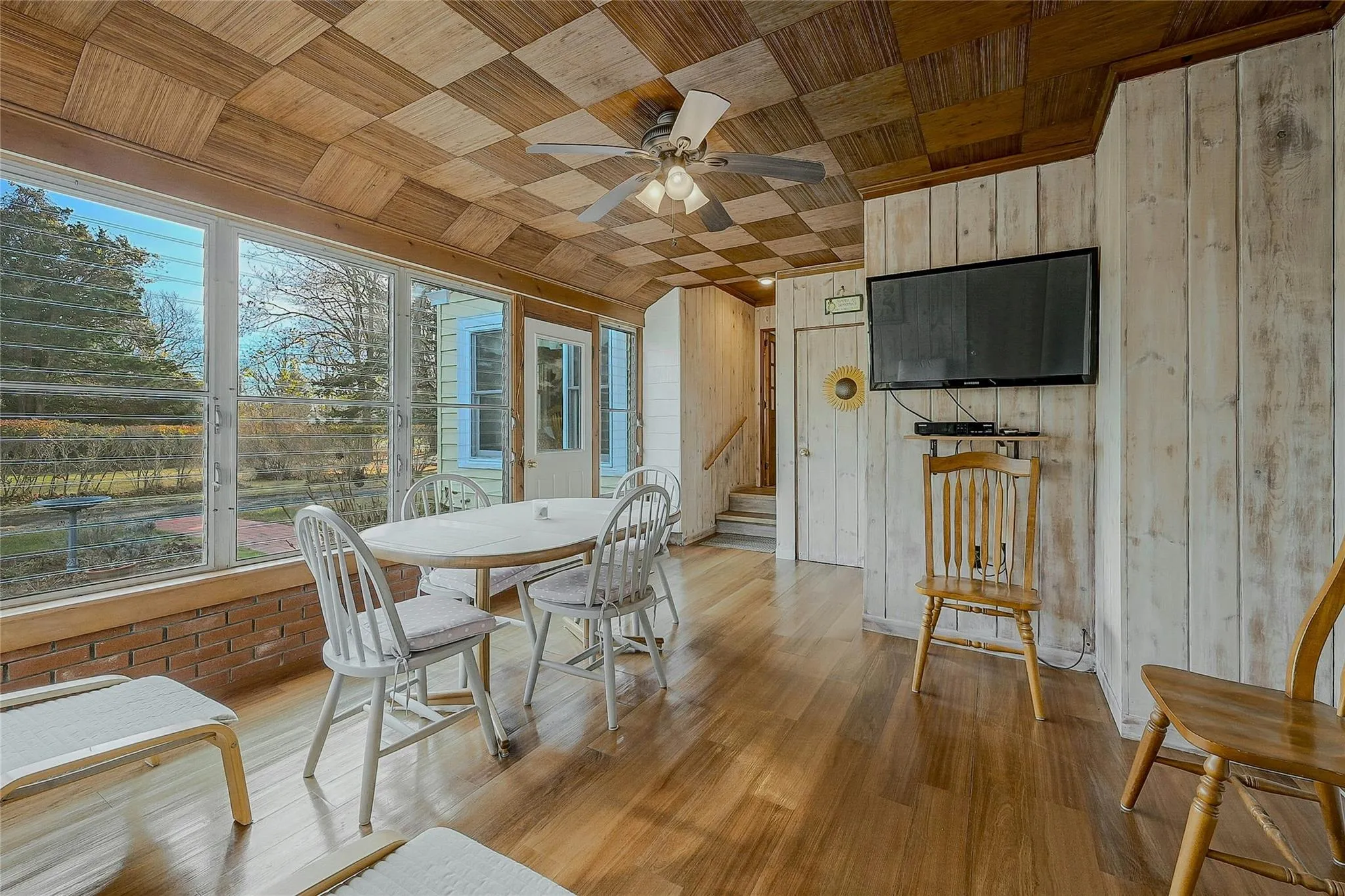 Dining area featuring wood walls, stairs, light wood-type flooring, wooden ceiling, and ceiling fan Dining area featuring wood walls, stairs, light wood-type flooring, wooden ceiling, and ceiling fan