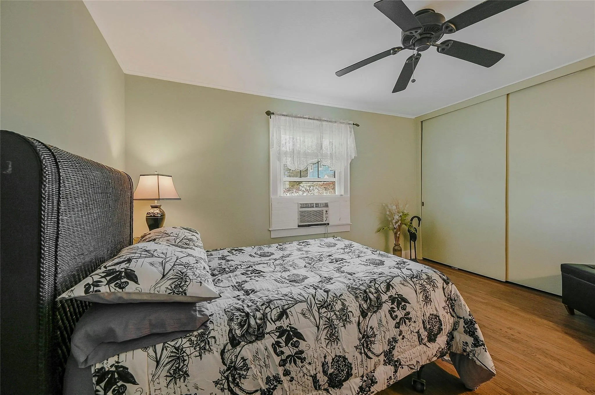 Bedroom featuring a closet, a ceiling fan, cooling unit, wood finished floors, and ornamental molding Bedroom featuring a closet, a ceiling fan, cooling unit, wood finished floors, and ornamental molding