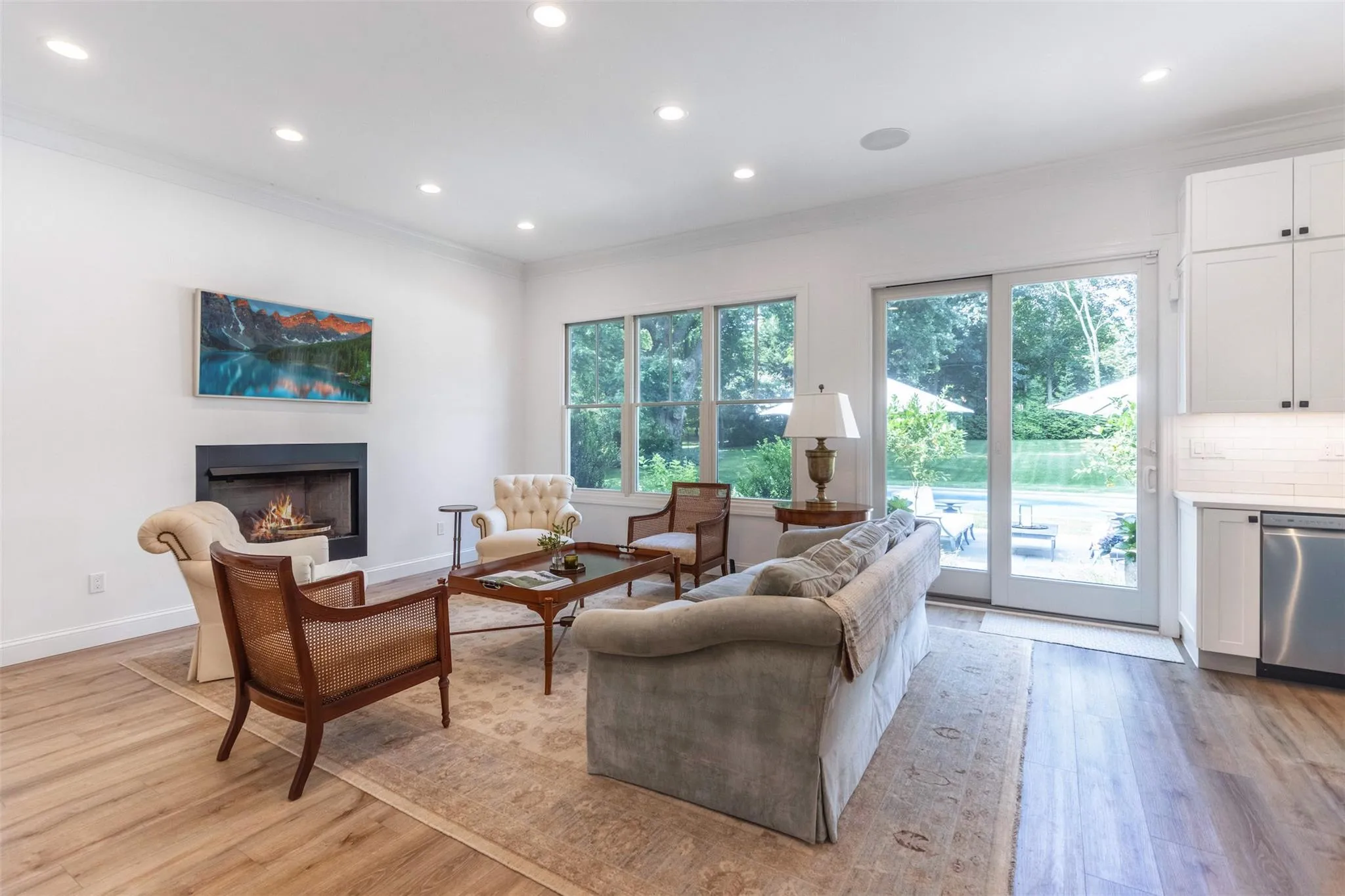 Living room featuring a warm lit fireplace, light wood-style flooring, baseboards, ornamental molding, and recessed lighting Living room featuring a warm lit fireplace, light wood-style flooring, baseboards, ornamental molding, and recessed lighting