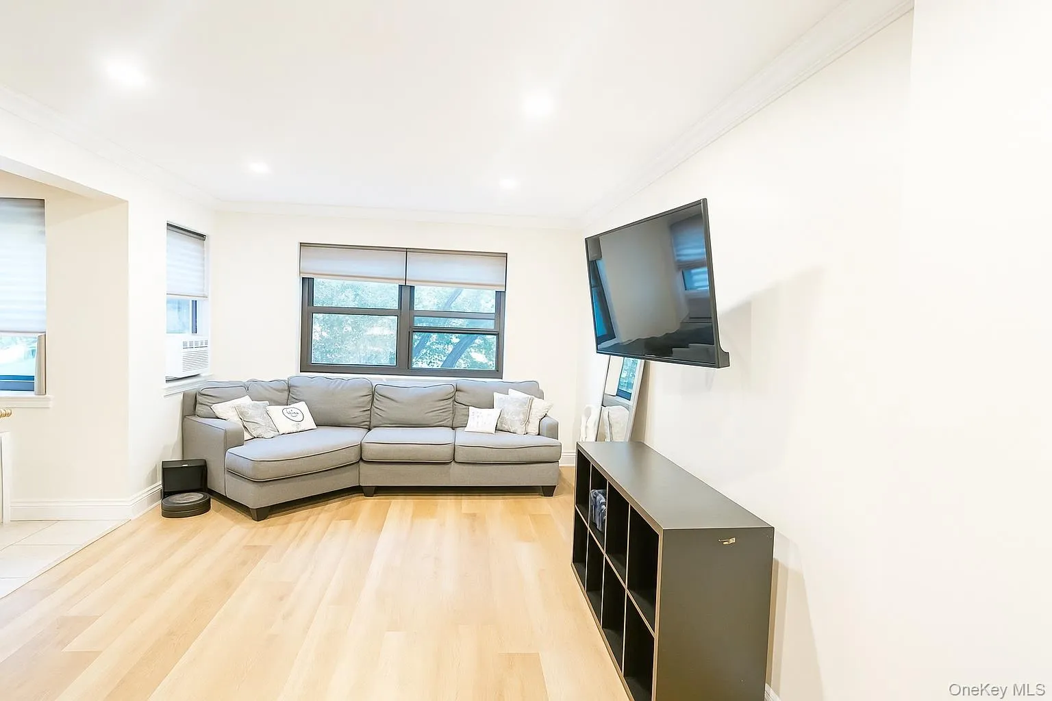 Living area with crown molding, light planked floors, and recessed lighting Living area with crown molding, light planked floors, and recessed lighting
