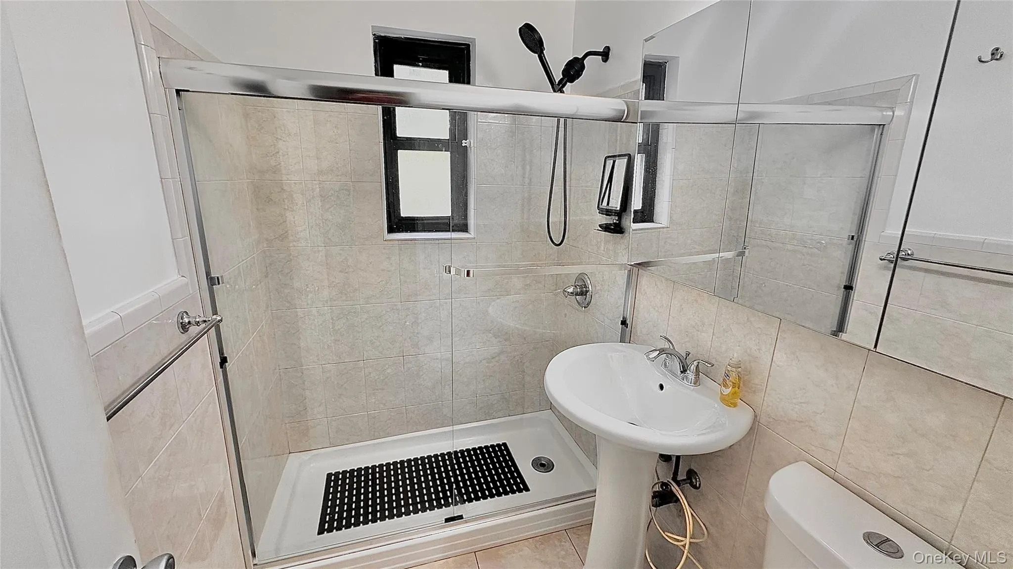 Bathroom featuring a shower stall and tile walls Bathroom featuring a shower stall and tile walls