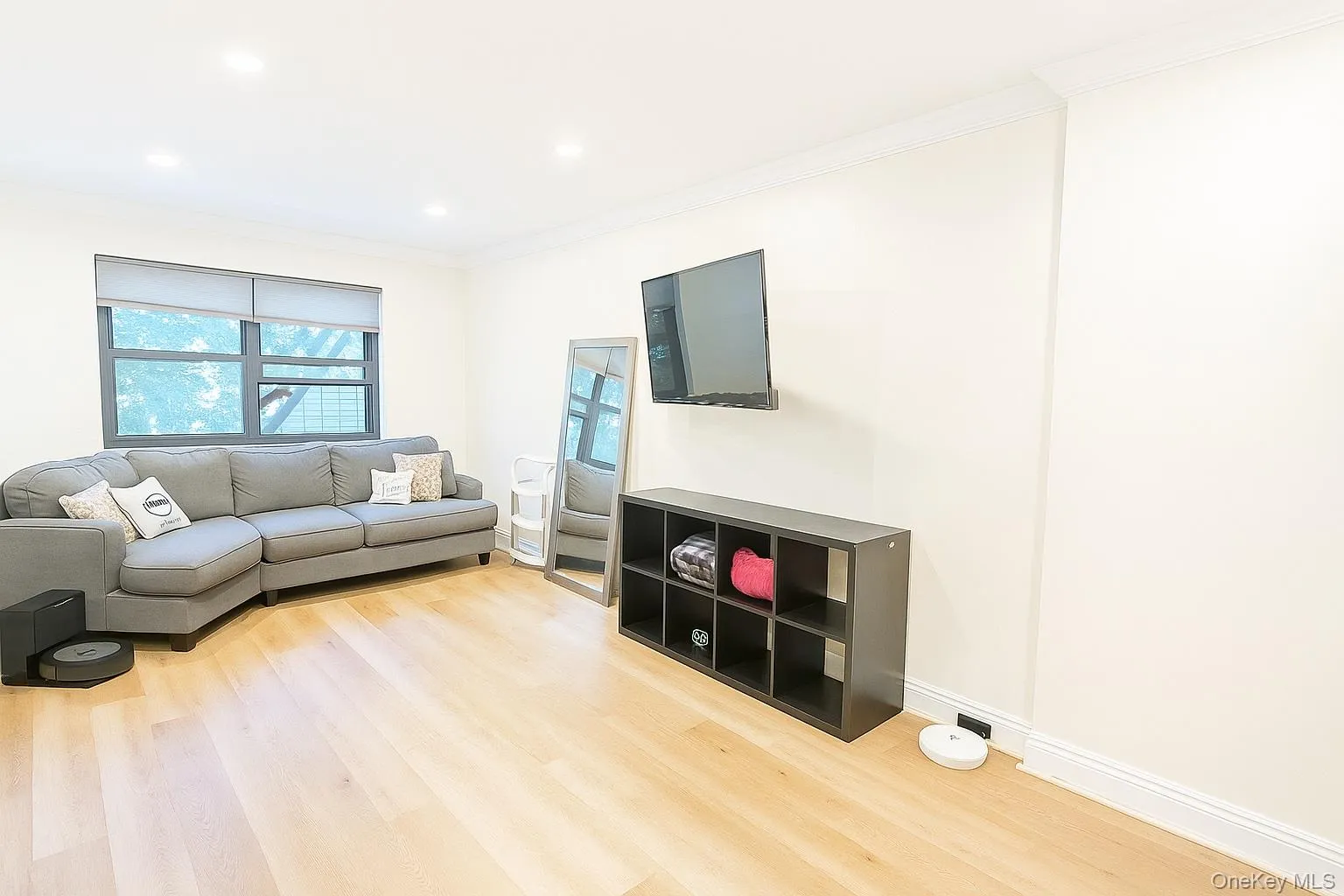Living area with light planked floors, ornamental molding, and recessed lighting Living area with light planked floors, ornamental molding, and recessed lighting