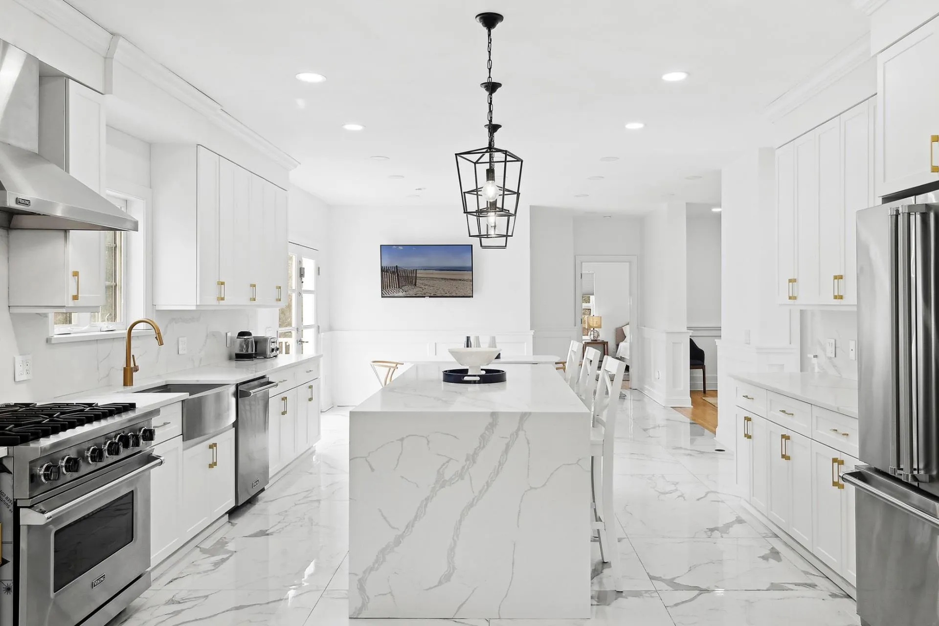 Kitchen with a center island, marble finish floor, a sink, wall chimney range hood, and appliances with stainless steel finishes Kitchen with a center island, marble finish floor, a sink, wall chimney range hood, and appliances with stainless steel finishes