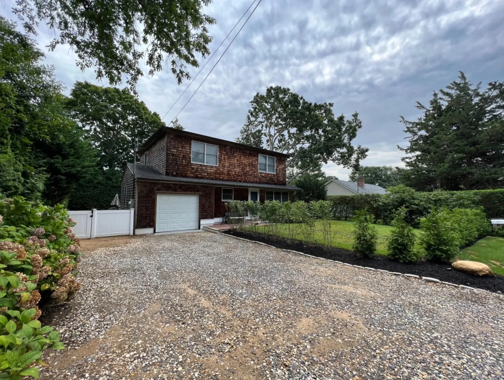 View of front facade with gravel driveway, a gate, a garage, and fence View of front facade with gravel driveway, a gate, a garage, and fence