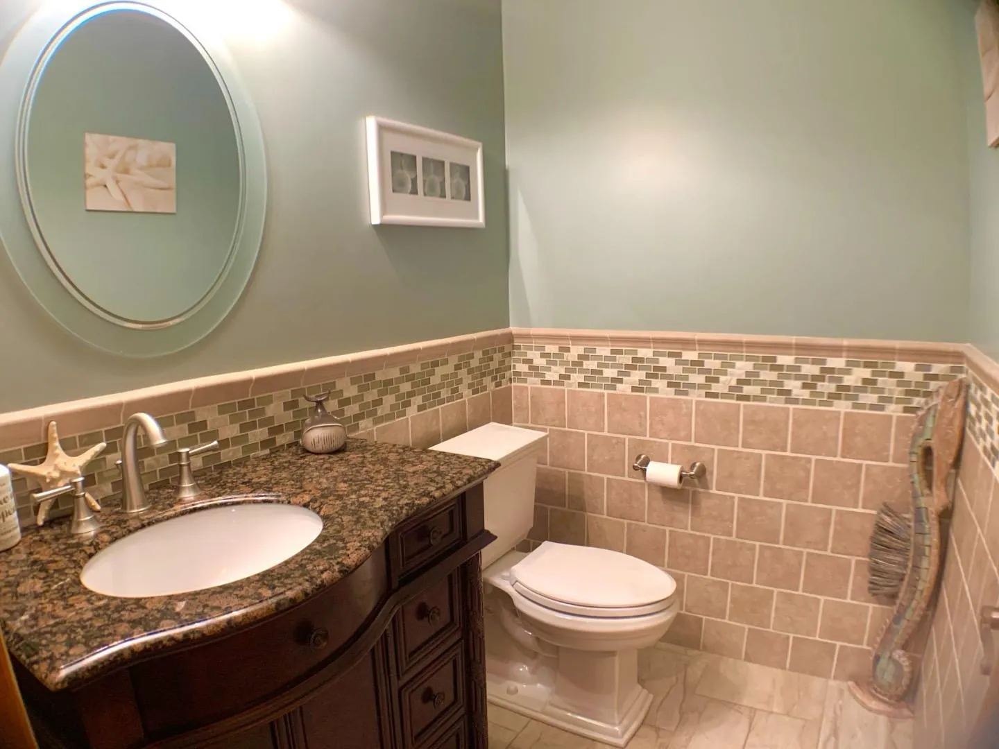 Half bath with vanity, tile walls, toilet, marble finish floor, and wainscoting Half bath with vanity, tile walls, toilet, marble finish floor, and wainscoting
