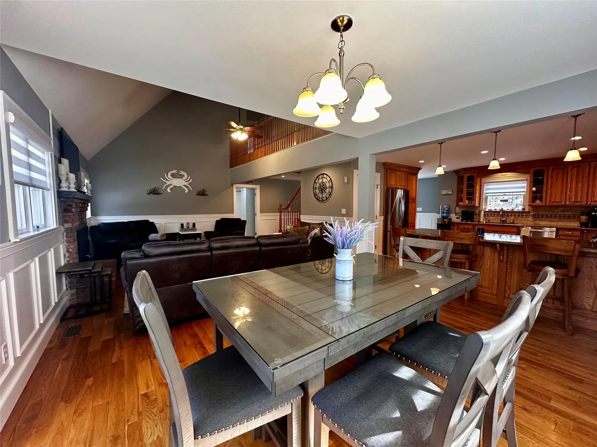 Dining space featuring lofted ceiling, light wood-type flooring, and ceiling fan with notable chandelier Dining space featuring lofted ceiling, light wood-type flooring, and ceiling fan with notable chandelier