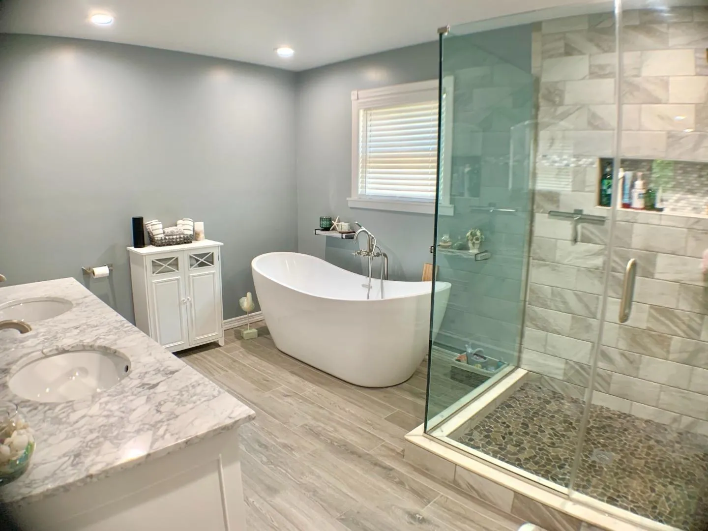Full bath with wood finish floors, a sink, a freestanding tub, and a stall shower Full bath with wood finish floors, a sink, a freestanding tub, and a stall shower