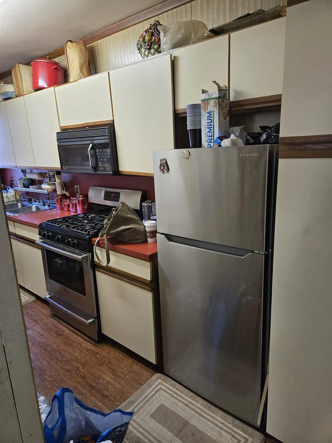 Kitchen featuring stainless steel appliances, a sink, dark countertops, white cabinets, and wood finished floors Kitchen featuring stainless steel appliances, a sink, dark countertops, white cabinets, and wood finished floors