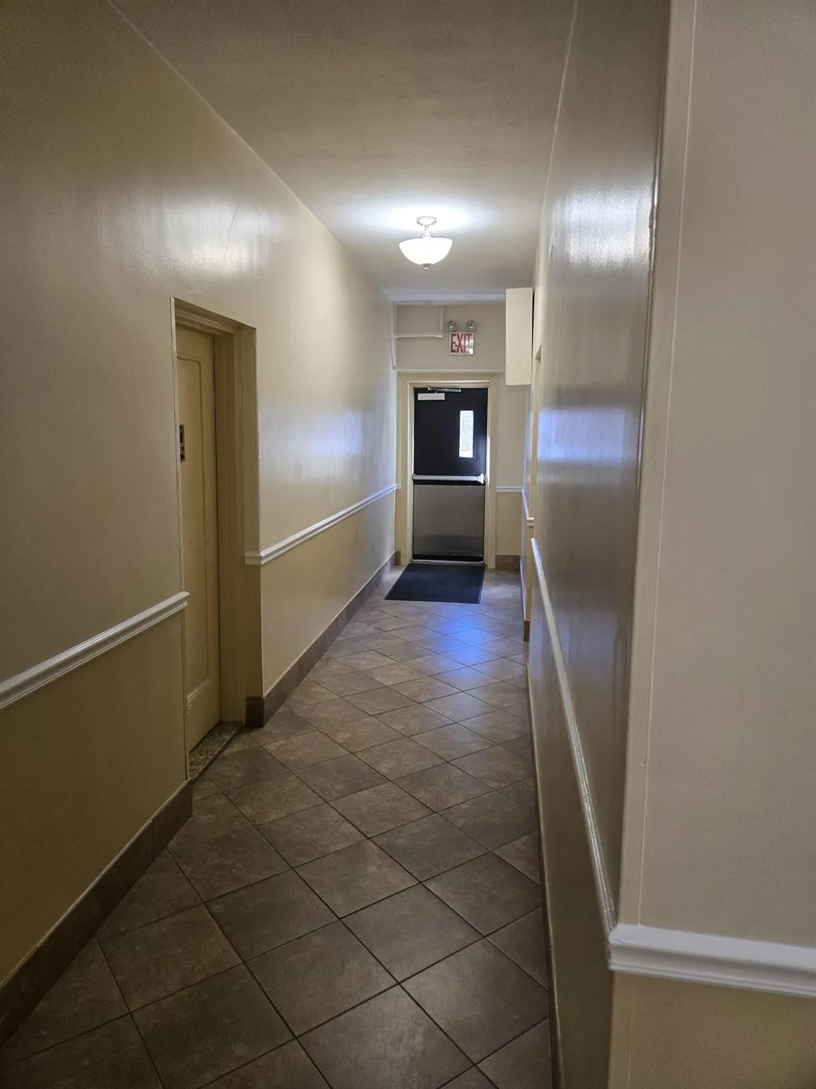 Hallway featuring dark tile patterned floors and baseboards Hallway featuring dark tile patterned floors and baseboards