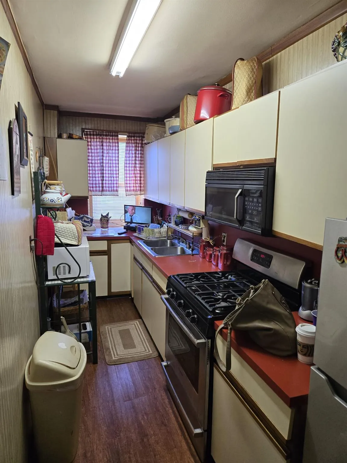 Kitchen featuring dark wood-style flooring, white cabinetry, a sink, and stainless steel appliances Kitchen featuring dark wood-style flooring, white cabinetry, a sink, and stainless steel appliances