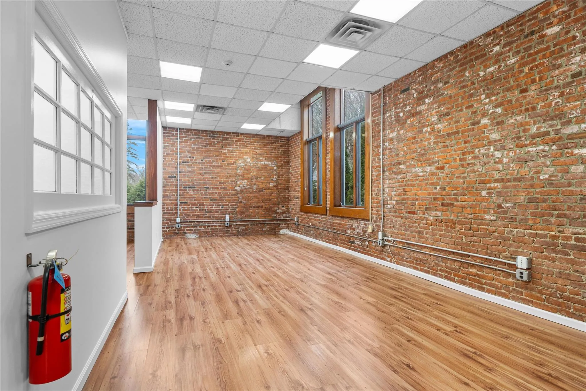 Empty room featuring wood finished floors, visible vents, and a paneled ceiling Empty room featuring wood finished floors, visible vents, and a paneled ceiling