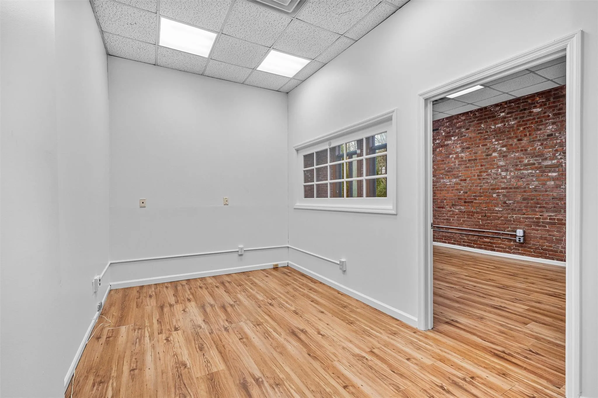 Spare room featuring light wood-type flooring, baseboards, and a paneled ceiling Spare room featuring light wood-type flooring, baseboards, and a paneled ceiling