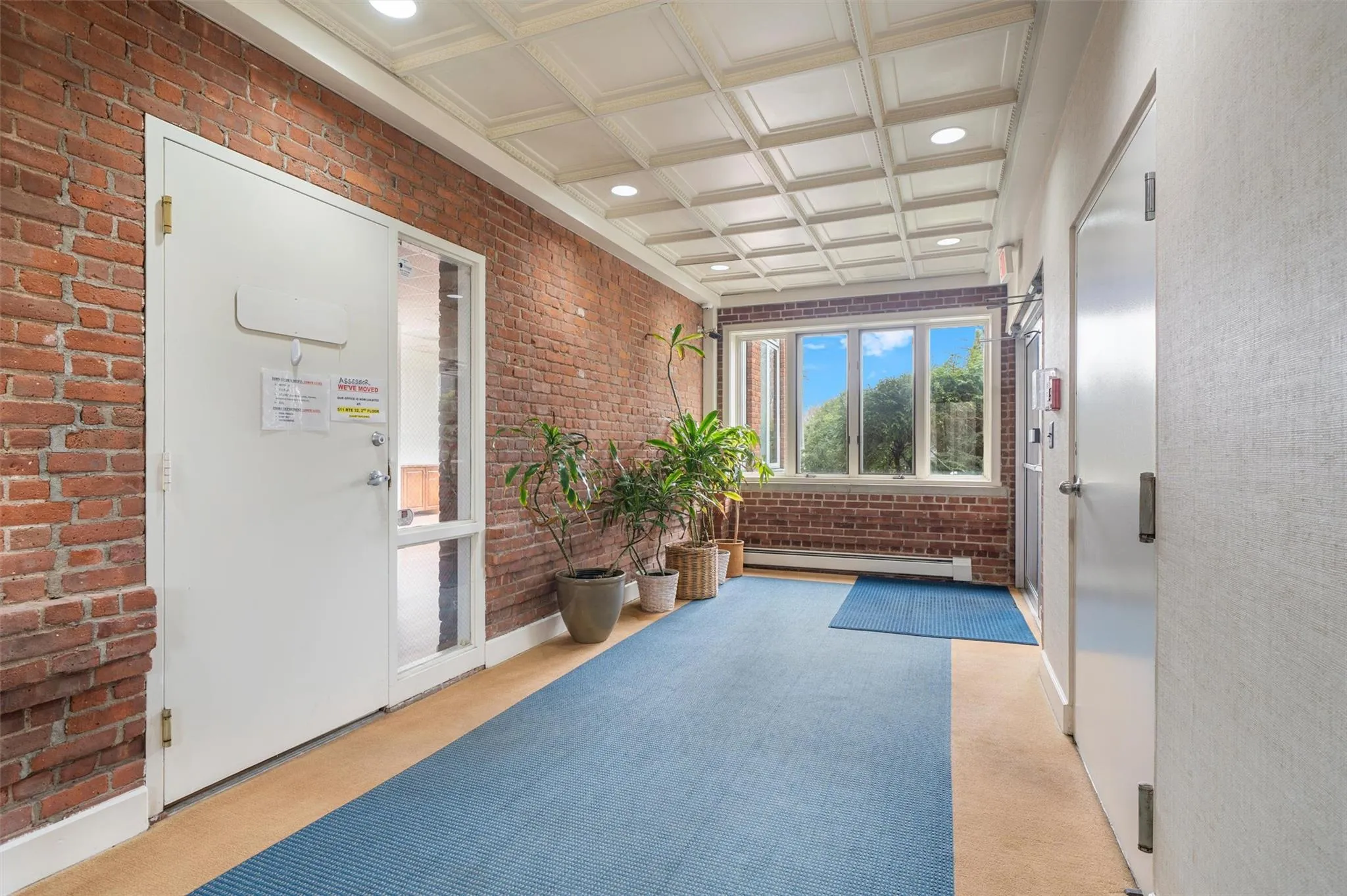 Corridor with carpet, recessed lighting, baseboard heating, brick wall, and coffered ceiling Corridor with carpet, recessed lighting, baseboard heating, brick wall, and coffered ceiling