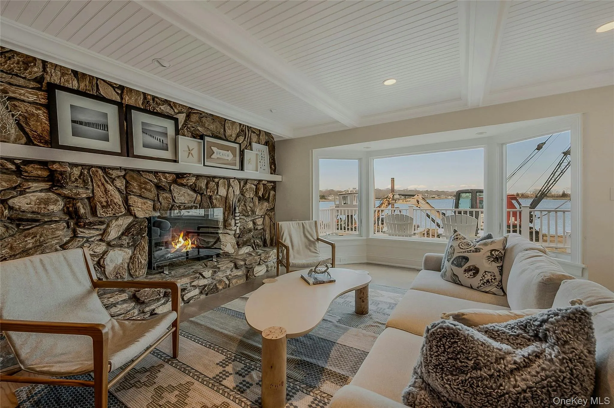 Living area featuring crown molding, beamed ceiling, and a stone fireplace Living area featuring crown molding, beamed ceiling, and a stone fireplace