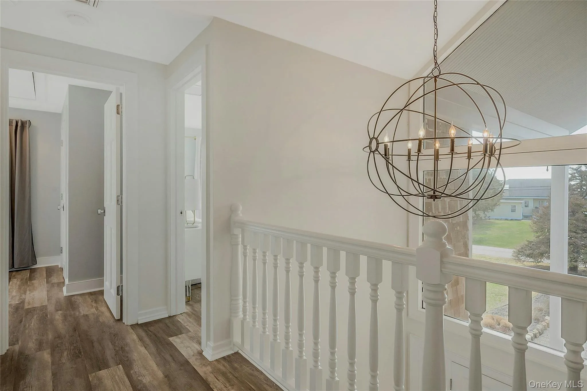 Hall featuring baseboards, lofted ceiling, wood finished floors, and an inviting chandelier Hall featuring baseboards, lofted ceiling, wood finished floors, and an inviting chandelier