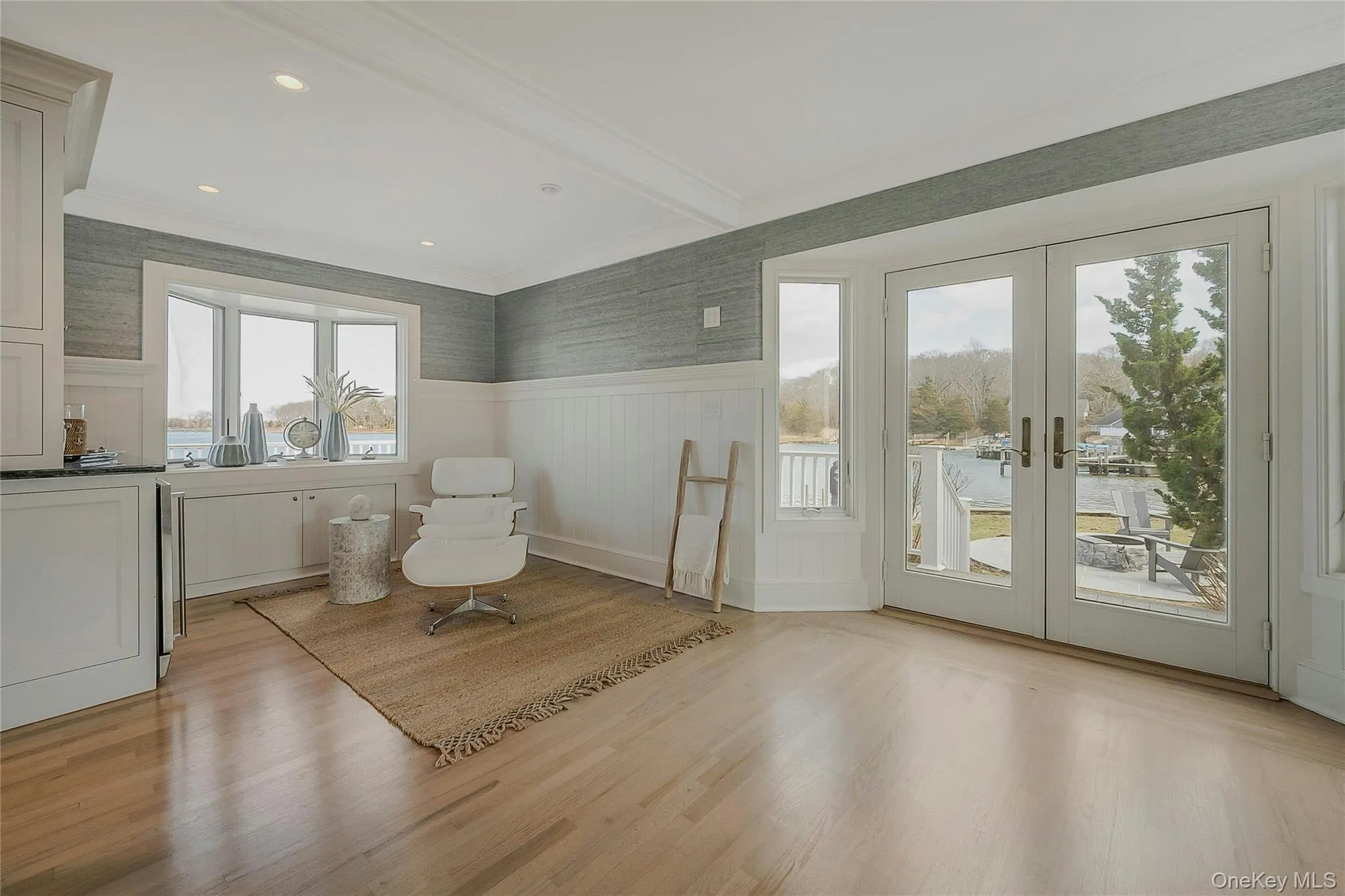 Sitting room with french doors, a wainscoted wall, crown molding, and light wood-style floors Sitting room with french doors, a wainscoted wall, crown molding, and light wood-style floors