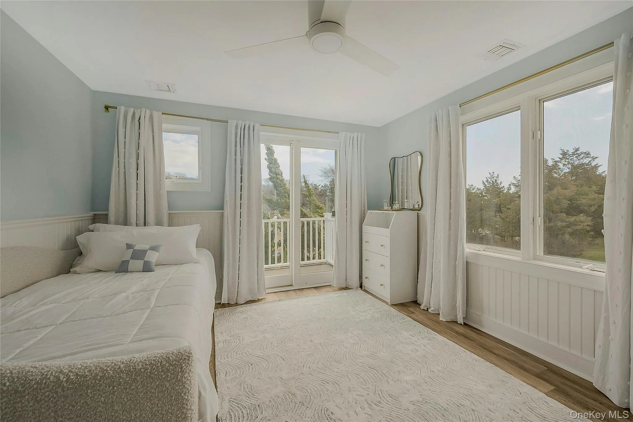 Bedroom with access to exterior, a ceiling fan, wood finished floors, wainscoting, and visible vents Bedroom with access to exterior, a ceiling fan, wood finished floors, wainscoting, and visible vents