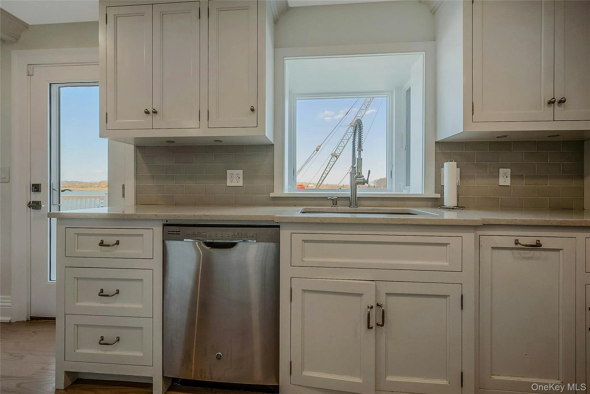 Kitchen featuring white cabinetry, light countertops, a sink, and stainless steel dishwasher Kitchen featuring white cabinetry, light countertops, a sink, and stainless steel dishwasher