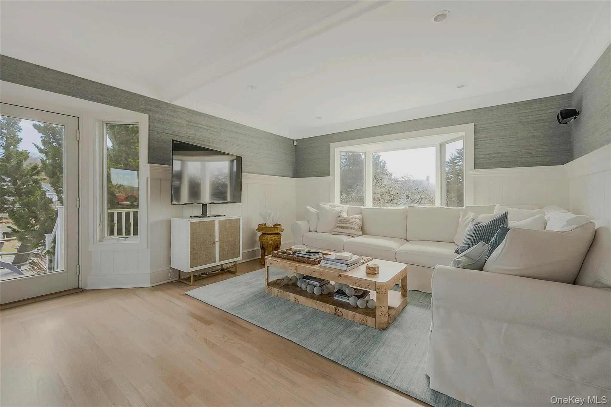 Living area featuring a wainscoted wall, a wealth of natural light, and wood finished floors Living area featuring a wainscoted wall, a wealth of natural light, and wood finished floors