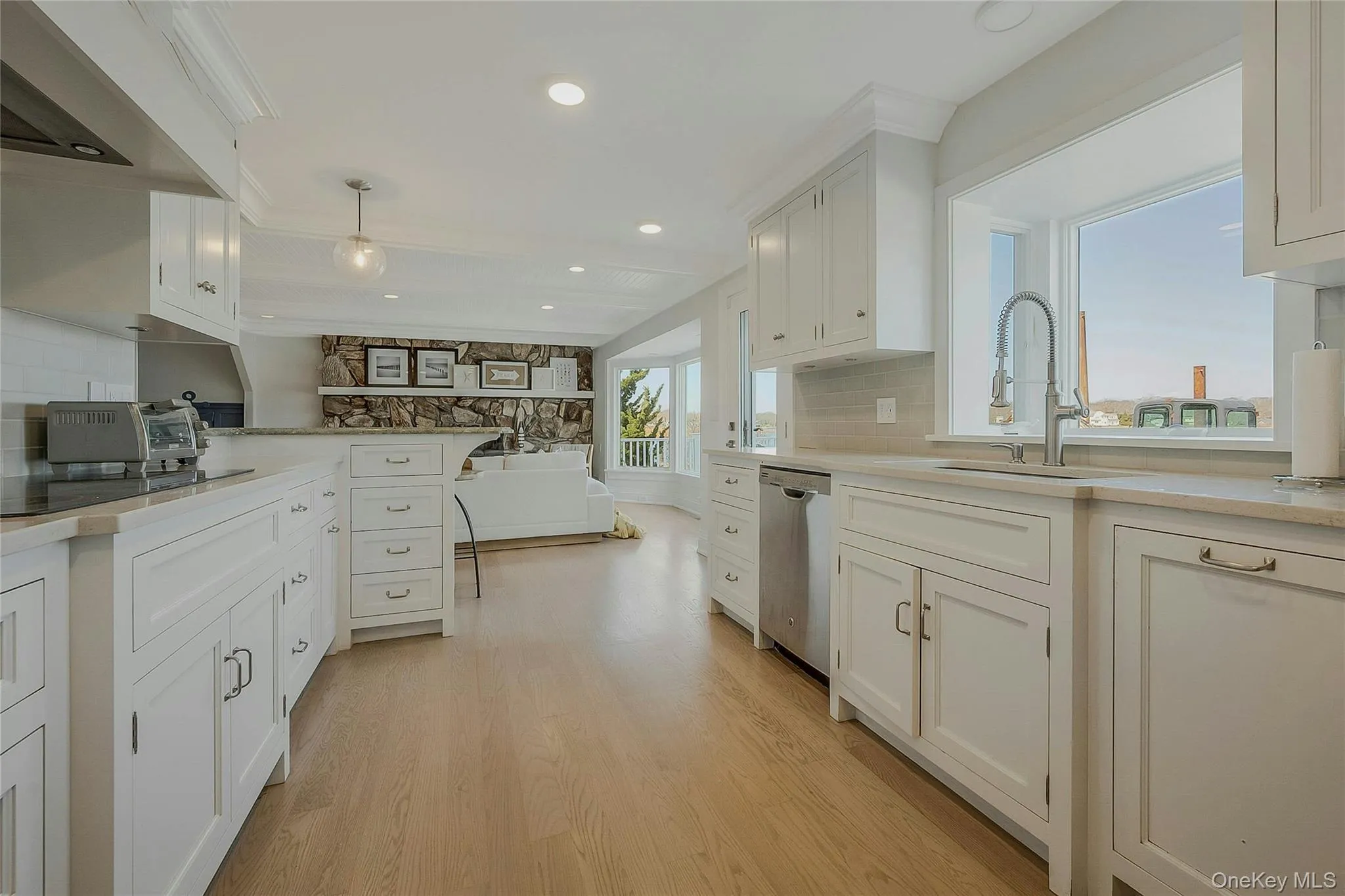 Kitchen featuring light wood-type flooring, black electric stovetop, a sink, dishwasher, and white cabinets Kitchen featuring light wood-type flooring, black electric stovetop, a sink, dishwasher, and white cabinets