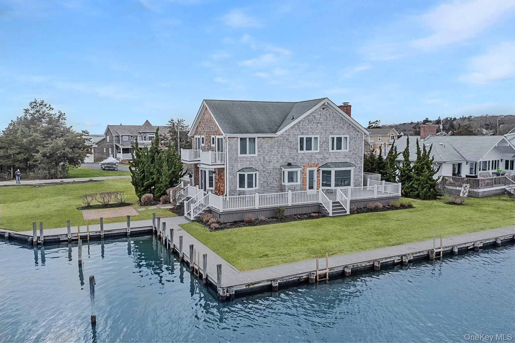 Rear view of property with a balcony, a chimney, a residential view, a lawn, and a deck with water view Rear view of property with a balcony, a chimney, a residential view, a lawn, and a deck with water view