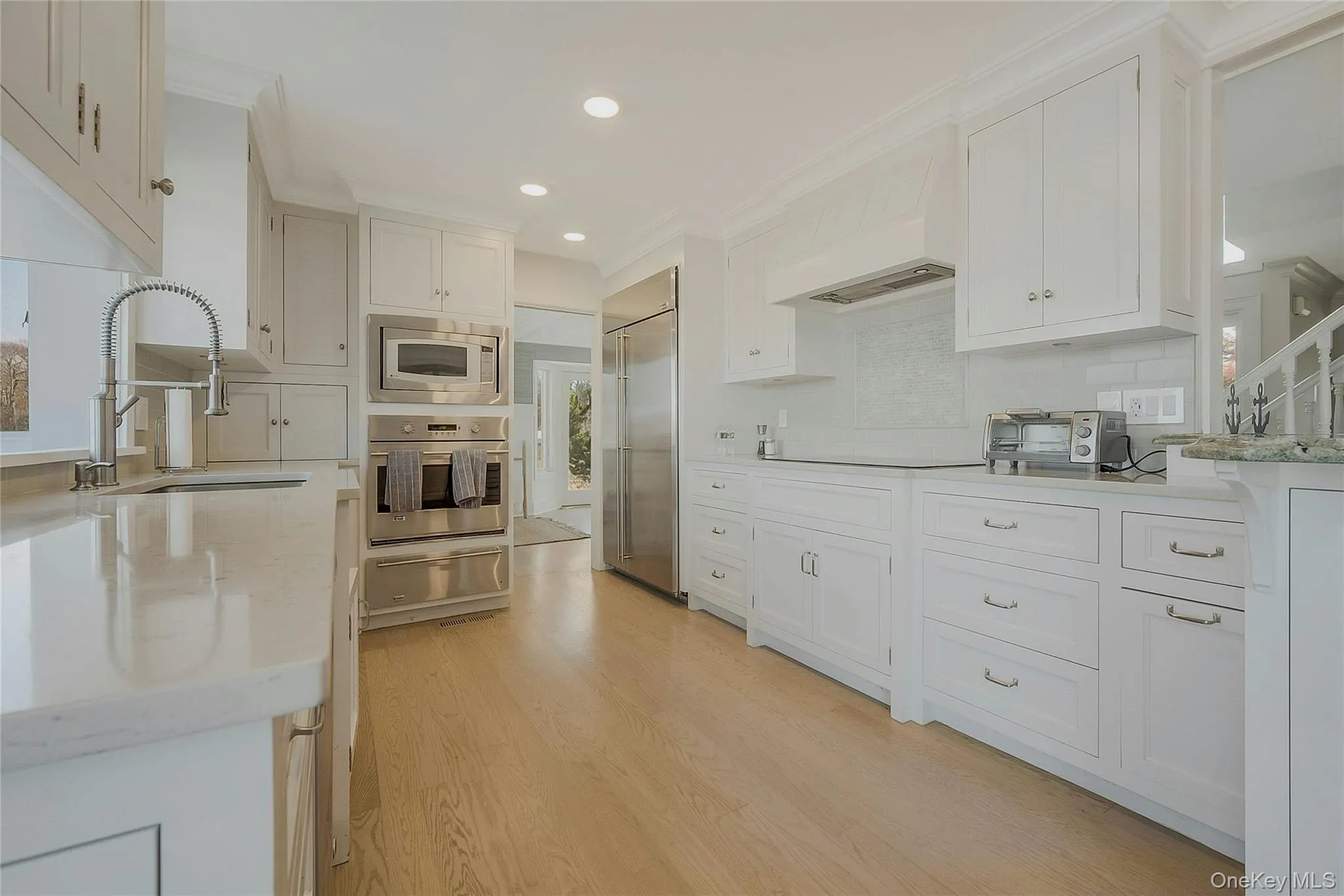 Kitchen featuring white cabinetry, a sink, a warming drawer, and built in appliances Kitchen featuring white cabinetry, a sink, a warming drawer, and built in appliances