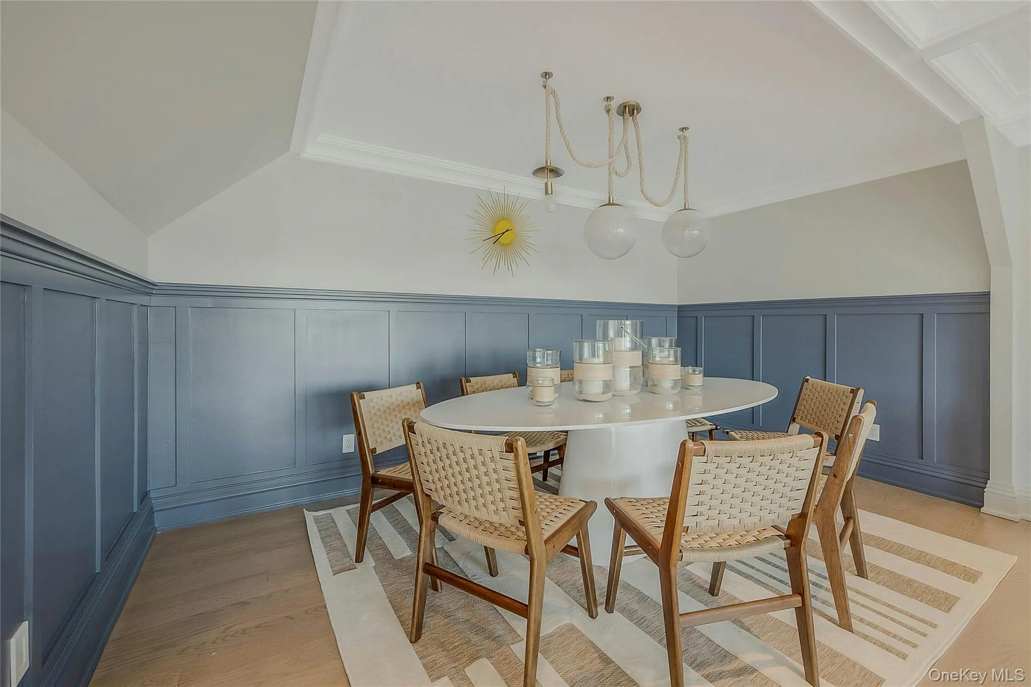 Dining area featuring a decorative wall, vaulted ceiling, ornamental molding, and light wood finished floors Dining area featuring a decorative wall, vaulted ceiling, ornamental molding, and light wood finished floors