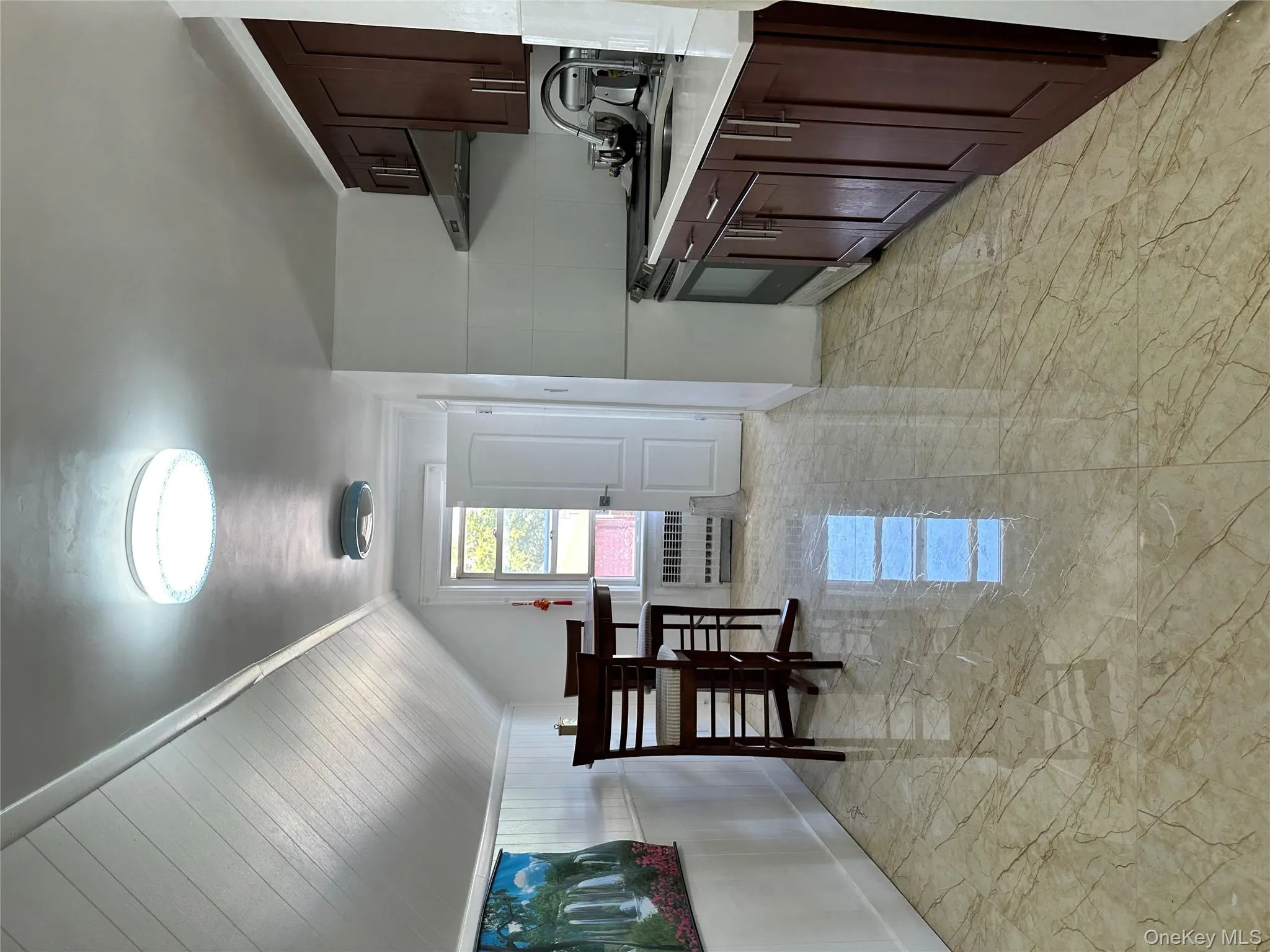Kitchen with light marble finish flooring, dark brown cabinetry, ventilation hood, range, and radiator heating unit Kitchen with light marble finish flooring, dark brown cabinetry, ventilation hood, range, and radiator heating unit