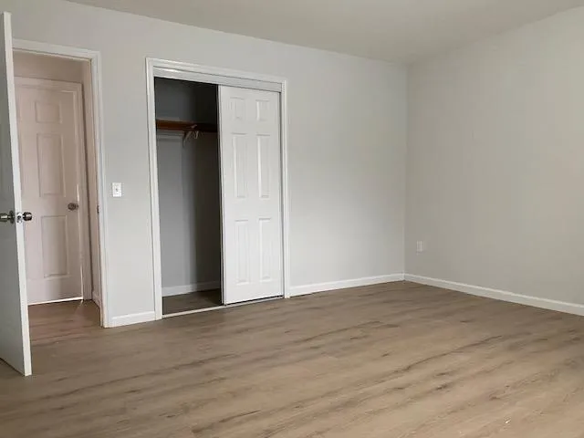 Unfurnished bedroom with a closet, baseboards, and wood finished floors Unfurnished bedroom with a closet, baseboards, and wood finished floors