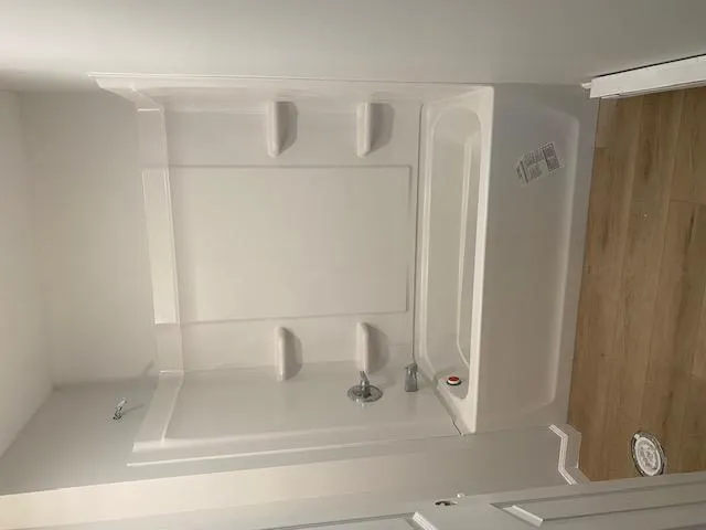 Bathroom with a baseboard radiator, bathtub / shower combination, and wood finished floors Bathroom with a baseboard radiator, bathtub / shower combination, and wood finished floors