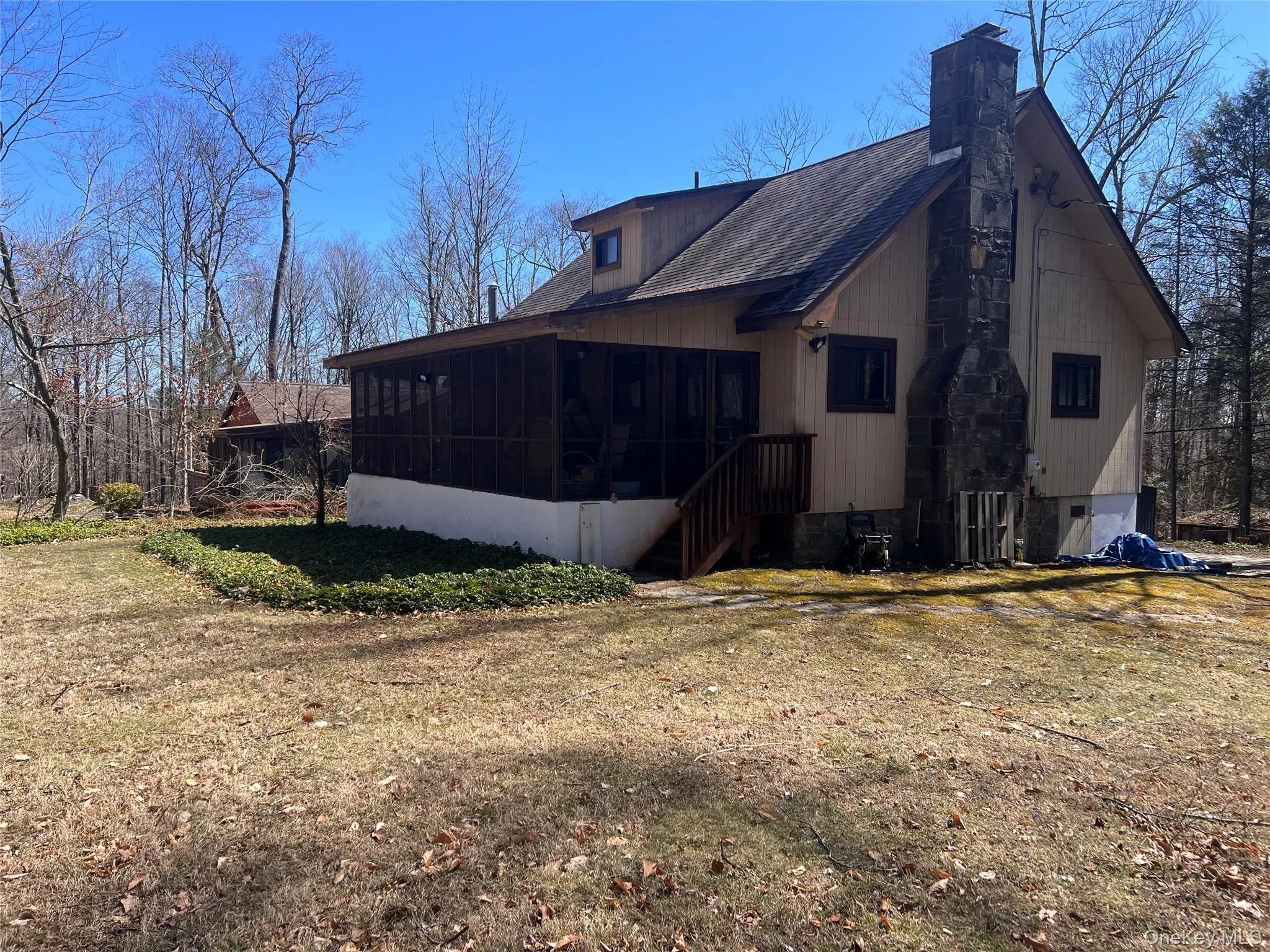 View of home's exterior featuring a lawn, a sunroom, a shingled roof, and a chimney View of home's exterior featuring a lawn, a sunroom, a shingled roof, and a chimney