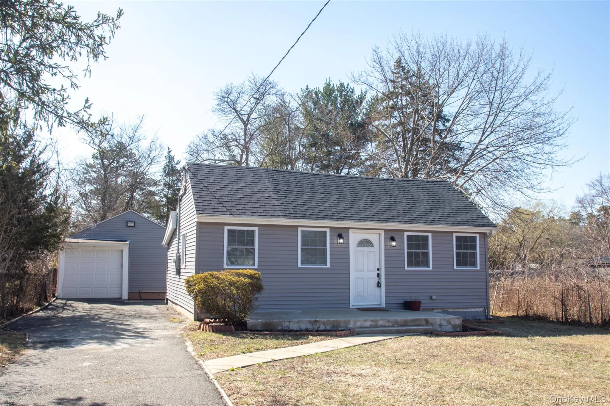 View of front facade featuring a garage, a front lawn, roof with shingles, driveway, and an outbuilding View of front facade featuring a garage, a front lawn, roof with shingles, driveway, and an outbuilding