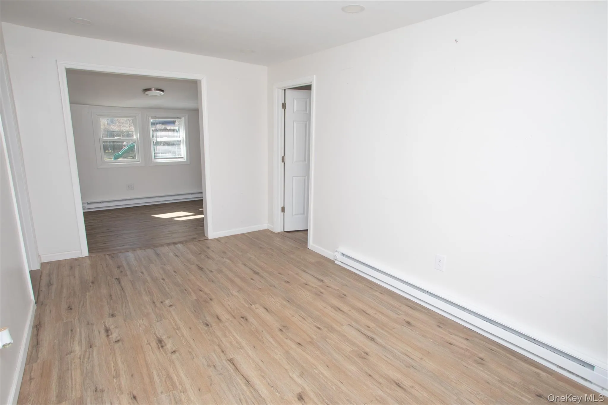 Empty room featuring baseboards, a baseboard heating unit, and wood finished floors Empty room featuring baseboards, a baseboard heating unit, and wood finished floors