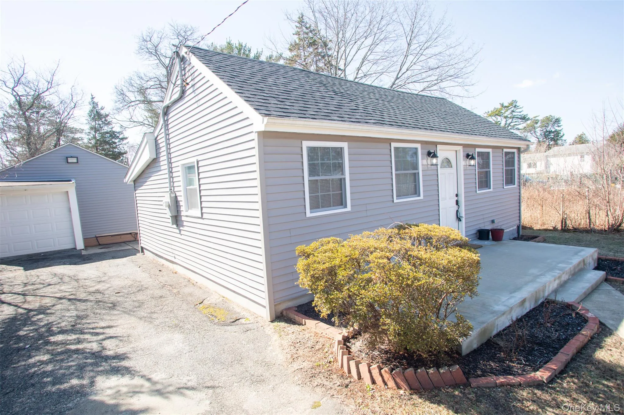 View of front of home featuring aphalt driveway, an outbuilding, a garage, and roof with shingles View of front of home featuring aphalt driveway, an outbuilding, a garage, and roof with shingles