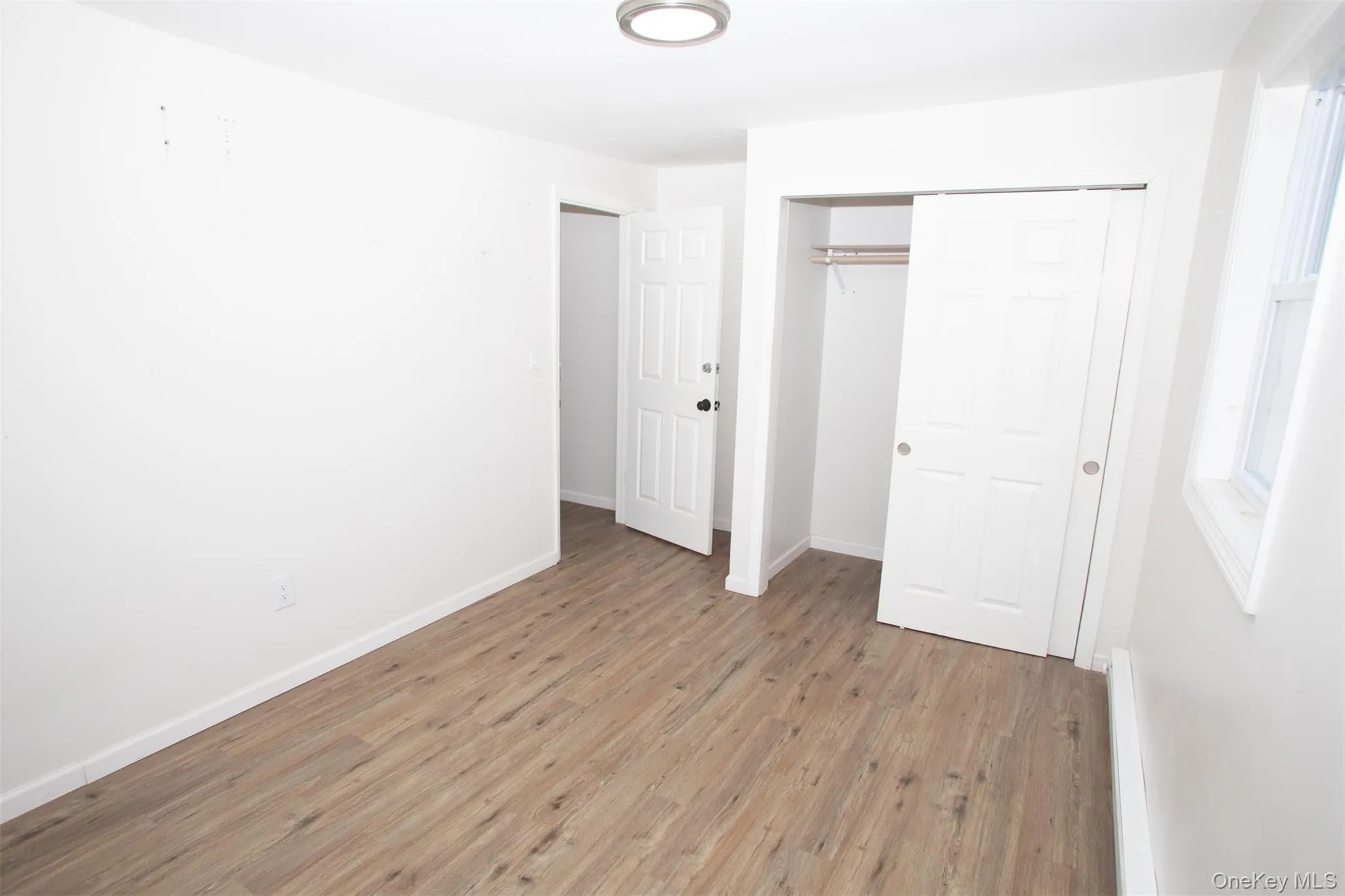 Unfurnished bedroom with light wood-style flooring, a closet, and baseboards Unfurnished bedroom with light wood-style flooring, a closet, and baseboards