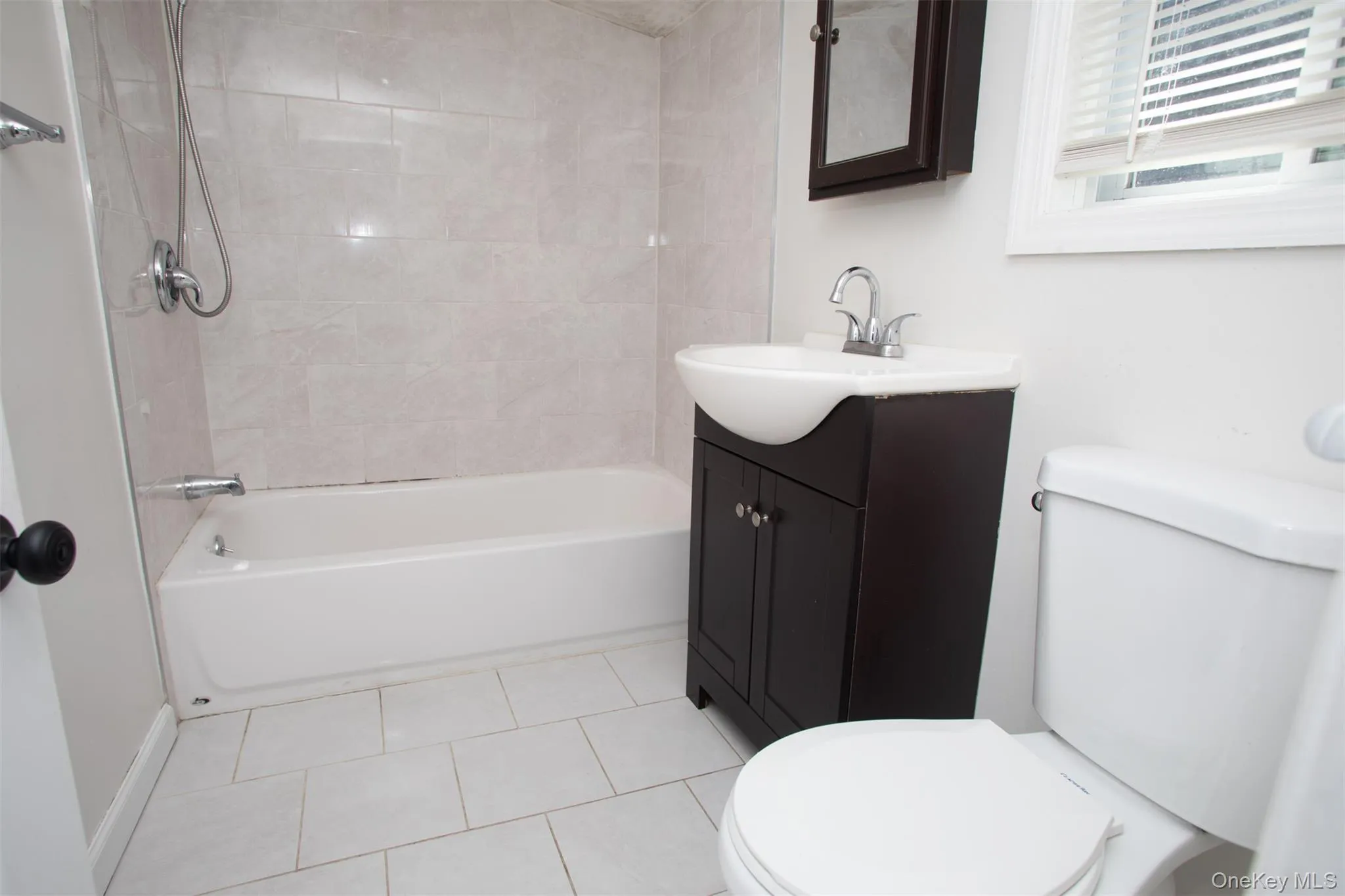 Bathroom featuring toilet, vanity, tile patterned floors, and tub / shower combination Bathroom featuring toilet, vanity, tile patterned floors, and tub / shower combination