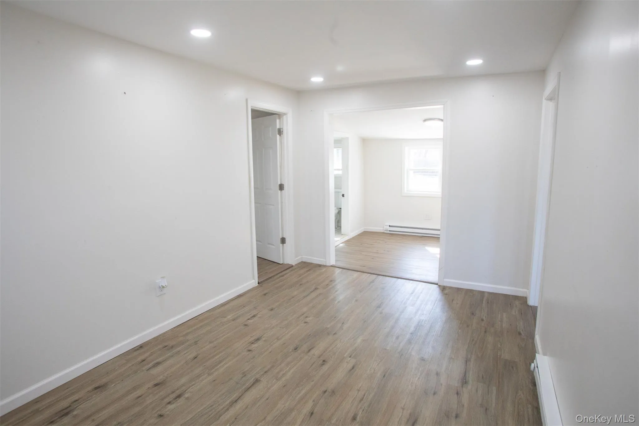 Unfurnished room with baseboards, wood finished floors, recessed lighting, and a baseboard radiator Unfurnished room with baseboards, wood finished floors, recessed lighting, and a baseboard radiator